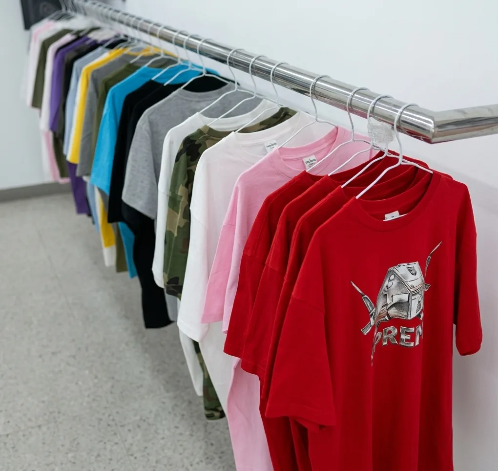 Un perchero de camisetas en la tienda, del verde oliva y el rosa hasta el rojo